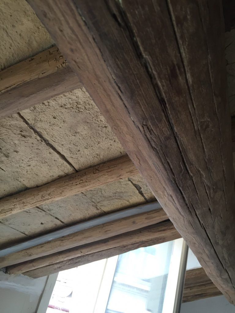 Travi in ​​legno e pannelli del soffitto consumati dal tempo sopra una luminosa apertura verso il cielo