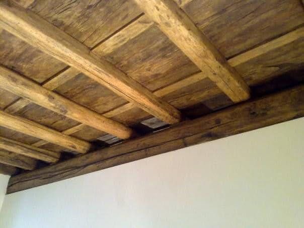 Soffitto con travi in ​​legno e assi rustiche sopra una parete bianca