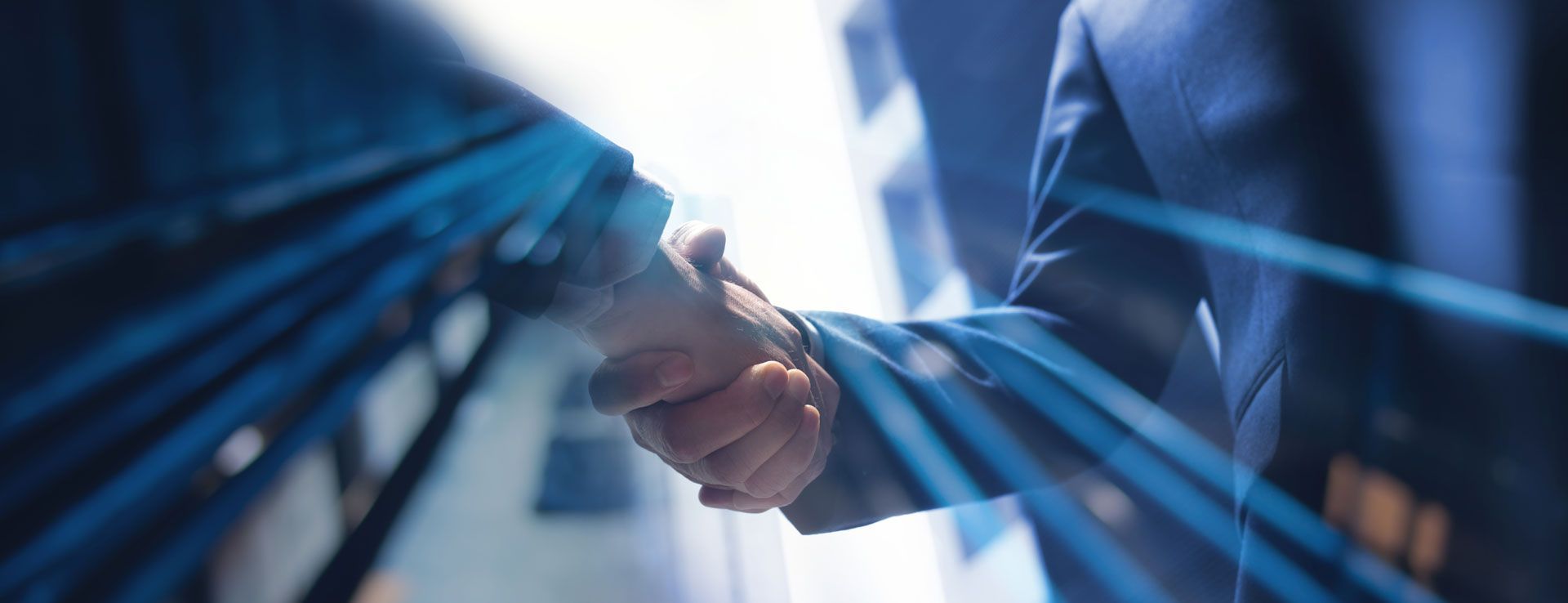 Two people in business suits shaking hands with blue light streaks in the background