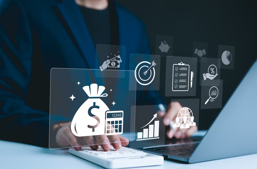Person in suit using laptop and calculator with financial icons overlayed.