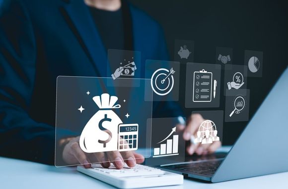 Person in suit using laptop and calculator with financial icons overlayed.