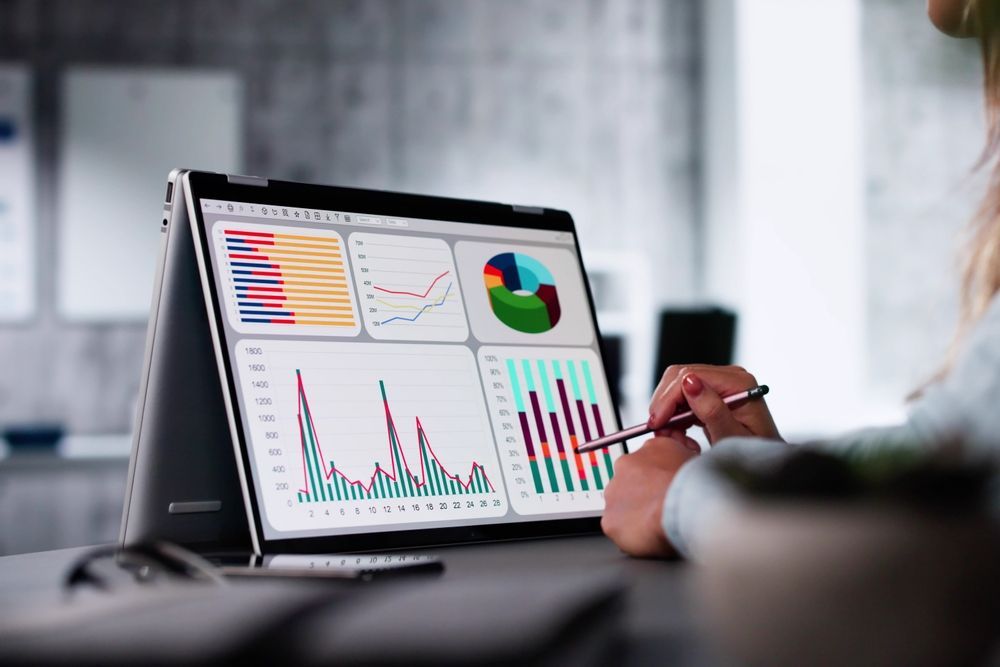 Person using a tablet displaying colorful financial charts and graphs.