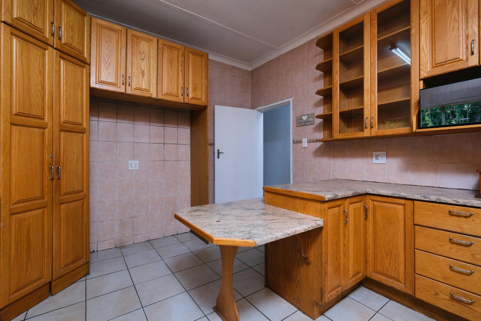 A person in a black hoodie and mask hands brown paper bags to a person at a doorway.