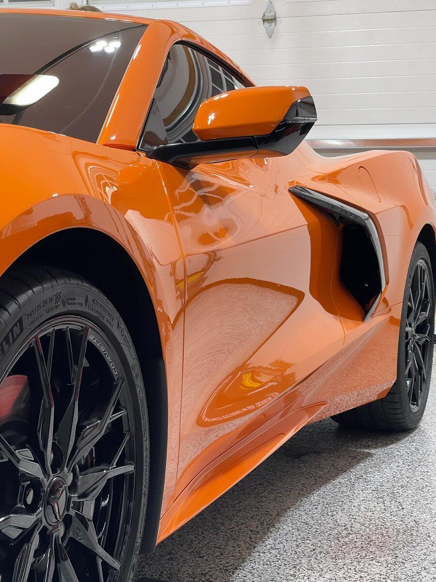 An orange sports car is parked in a garage.