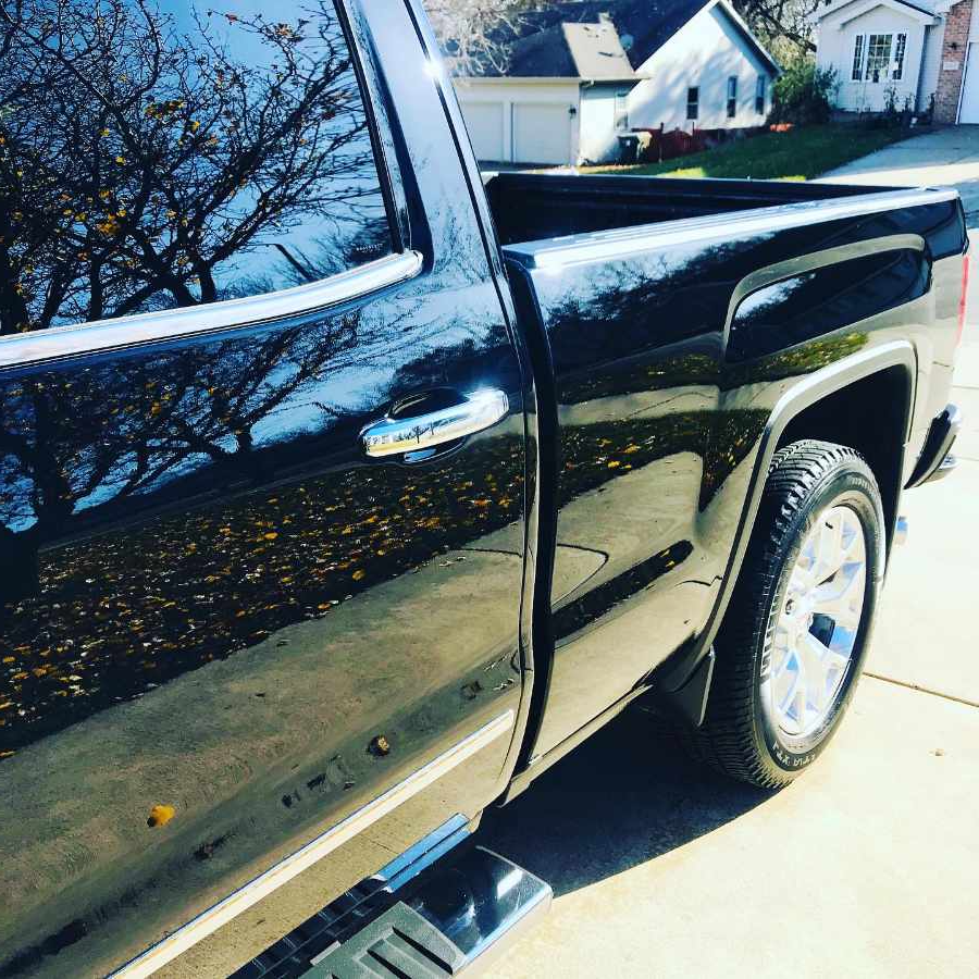 side of a polished black gmc in a driveway