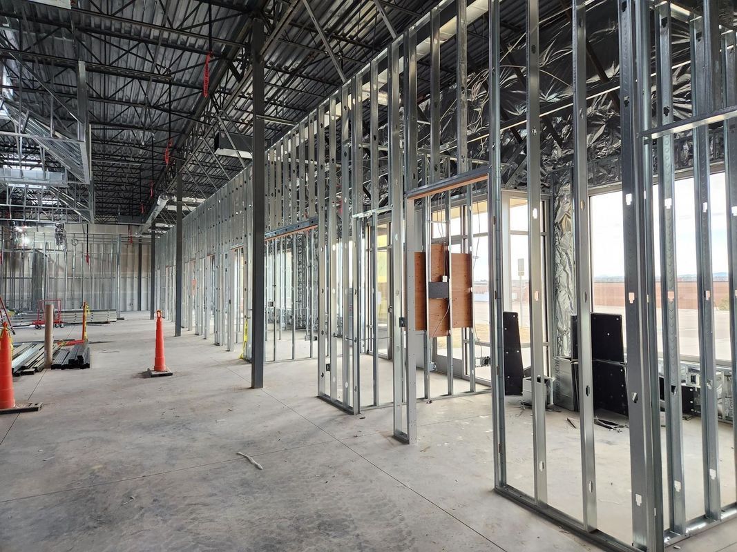 Interior view of a building under construction with metal studs forming walls and ceiling exposed.