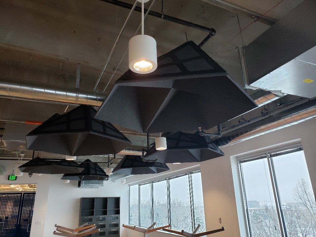 Black geometric ceiling fixtures with white pendant lights, over large windows with snowy outdoor view.