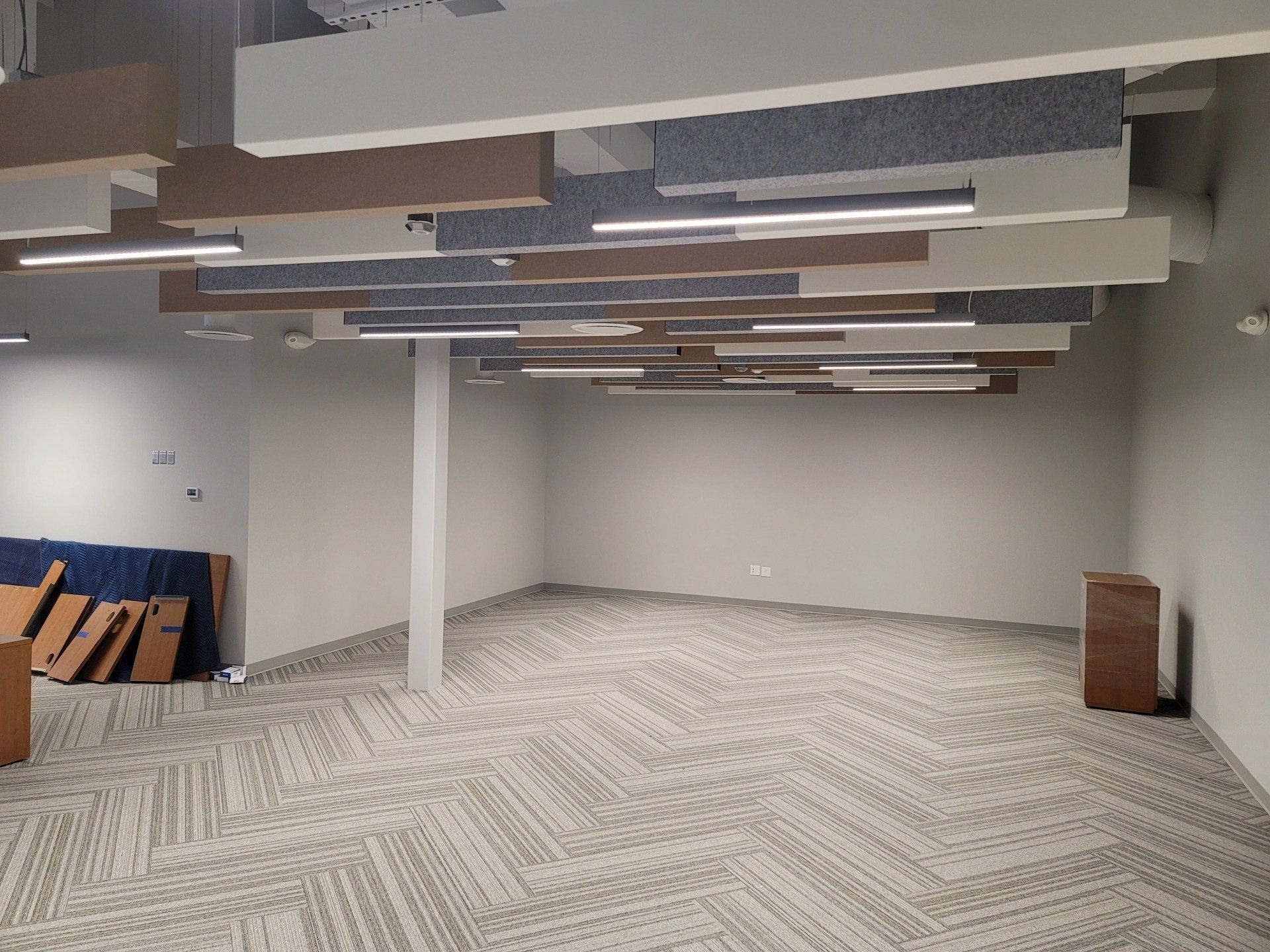 Empty room with acoustic panels, carpet, and a support beam.