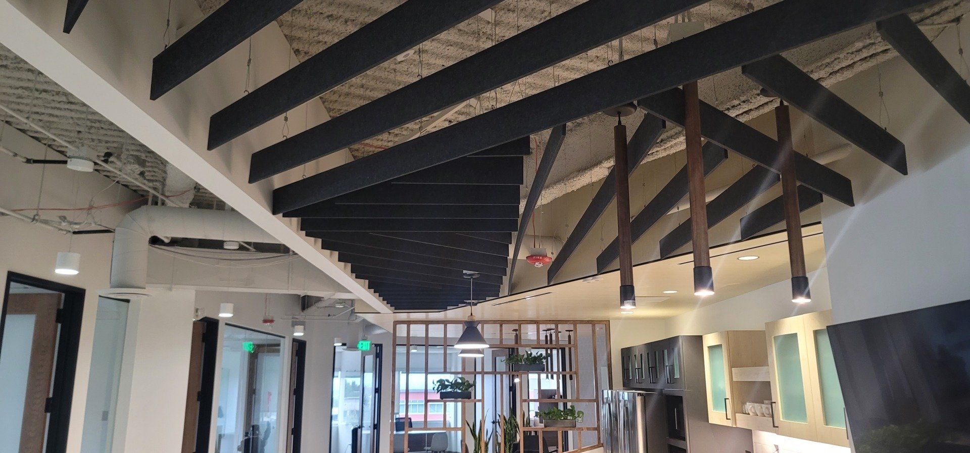 Interior view with a ceiling of exposed beams, hanging lights, and a glass-paneled room divider.