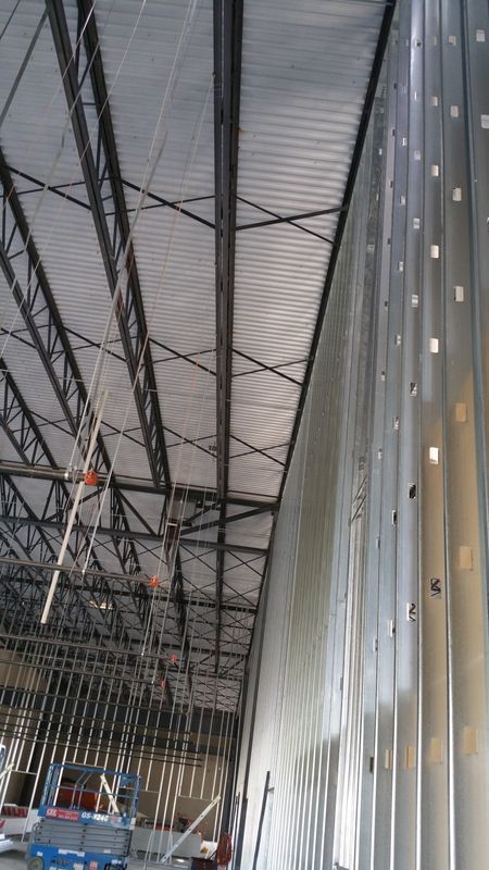 Interior view of a building under construction; metal siding, exposed beams, and corrugated roofing.