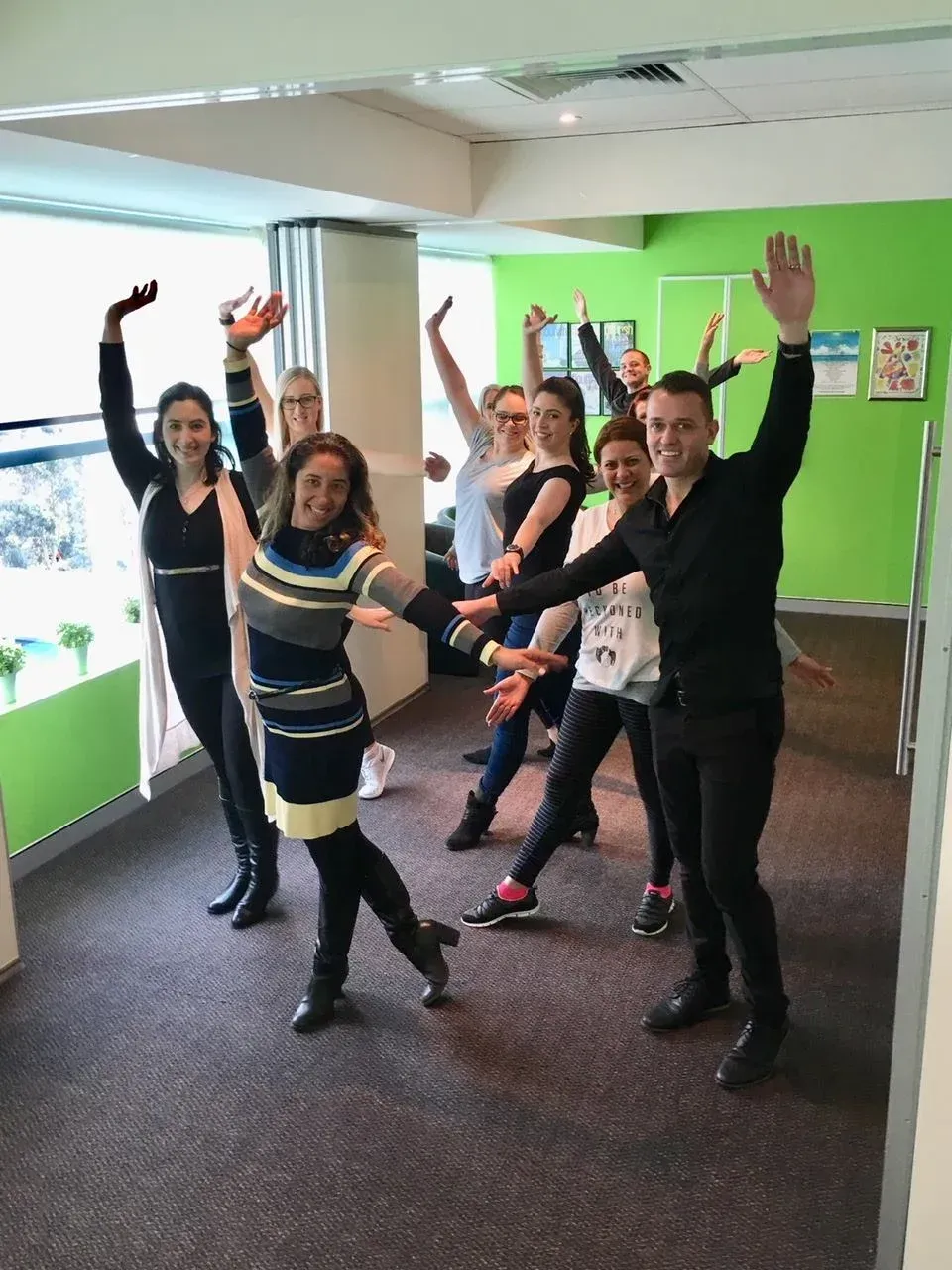 A group of people are standing in a room with their arms in the air.