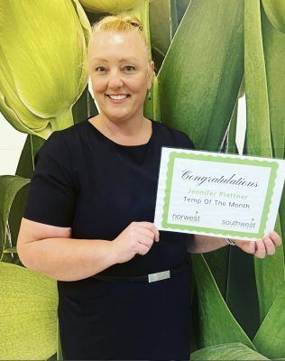 A woman is holding a certificate in front of a green background.