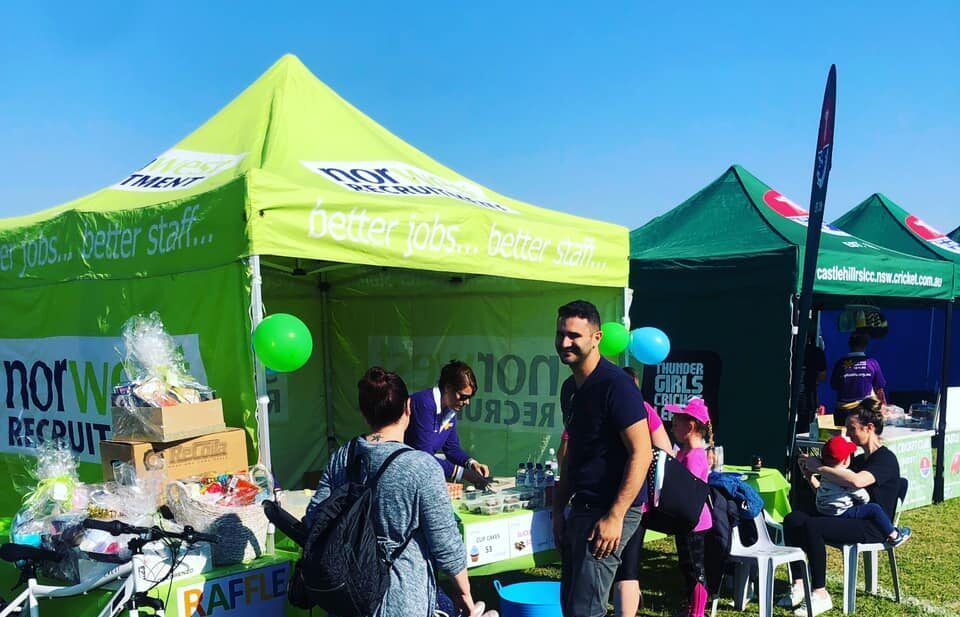 A group of people are standing in front of a green tent.