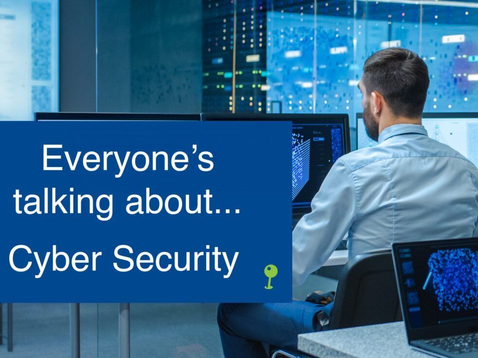 A man is sitting in front of a computer with a sign that says everyone 's talking about cyber security