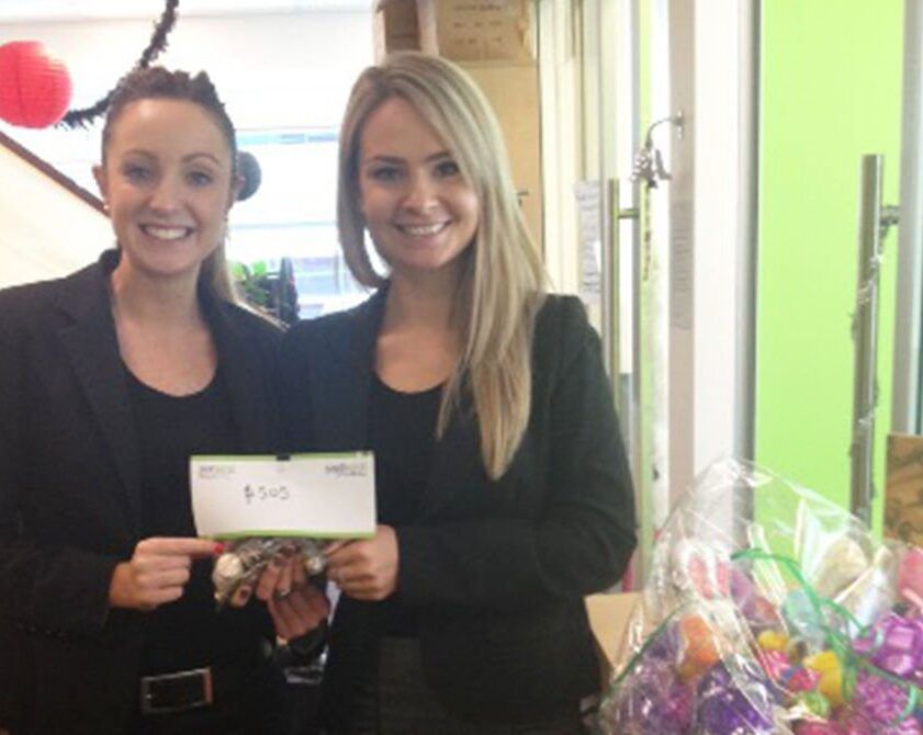 Two women are standing next to each other and one is holding a check for $ 500