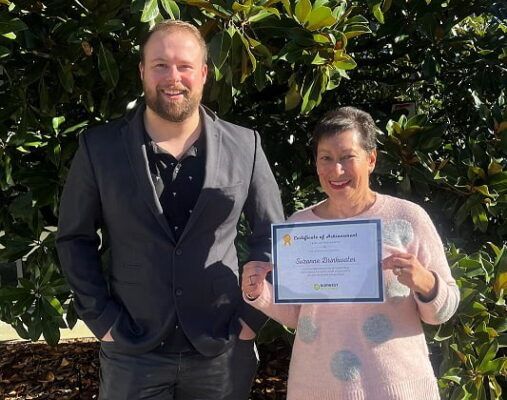 A man and a woman are standing next to each other holding a certificate.