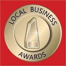 A gold coin with a glass trophy inside of it that says local business awards.