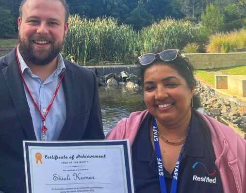 A man and a woman are holding a certificate of achievement