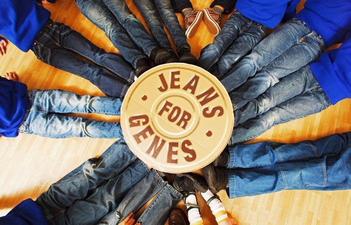 A group of people are laying in a circle around a sign that says jeans for genes