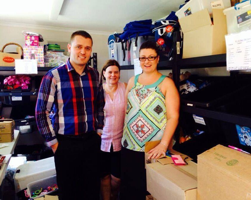 A man and two women are posing for a picture in a room full of boxes