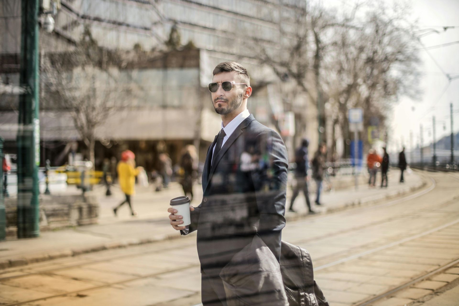 A man in a suit and tie is walking down the street holding a cup of coffee.