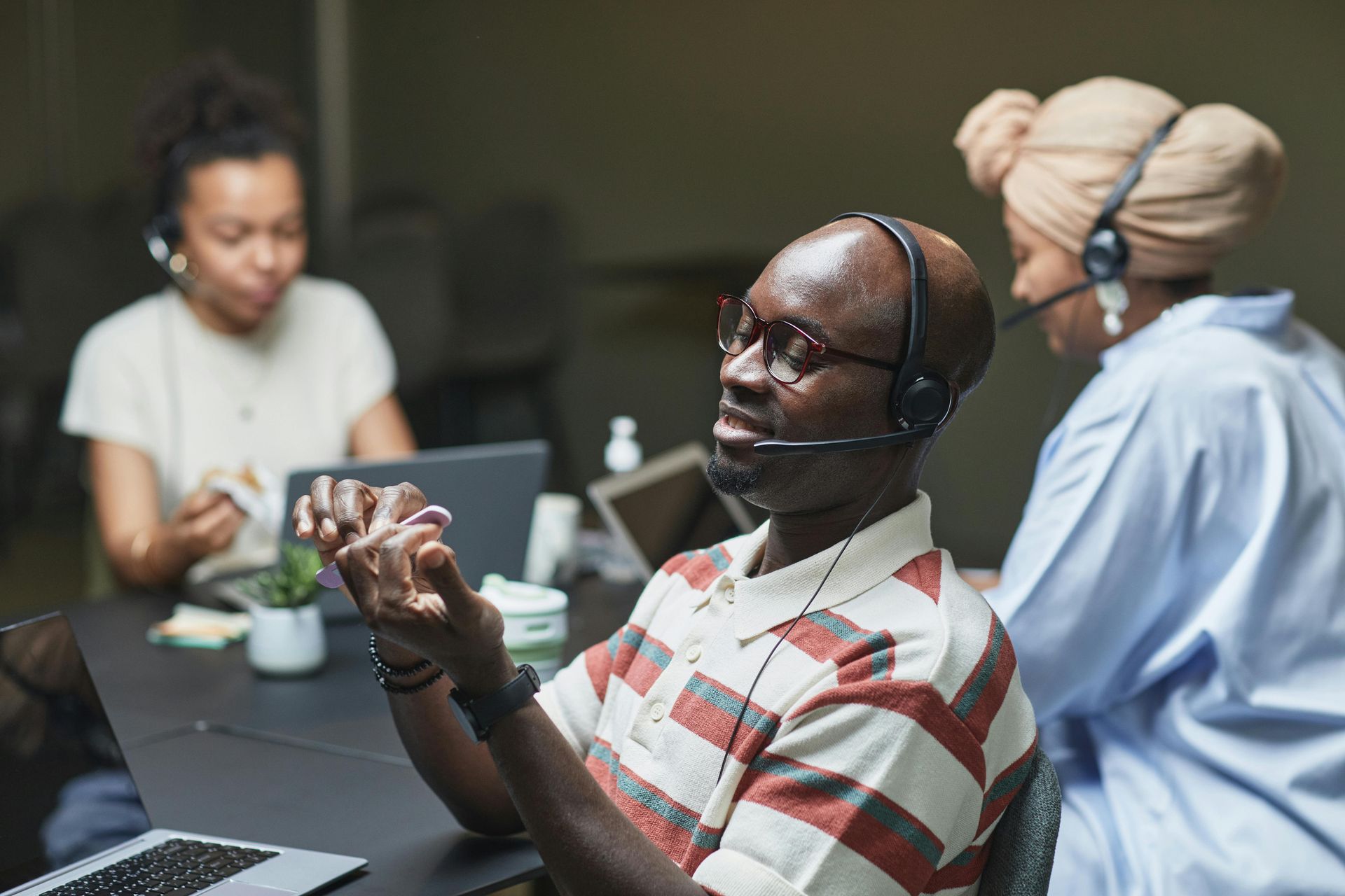 A man wearing a headset is sitting at a table with other people.