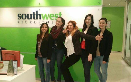 A group of women standing in front of a southwest recruiting sign
