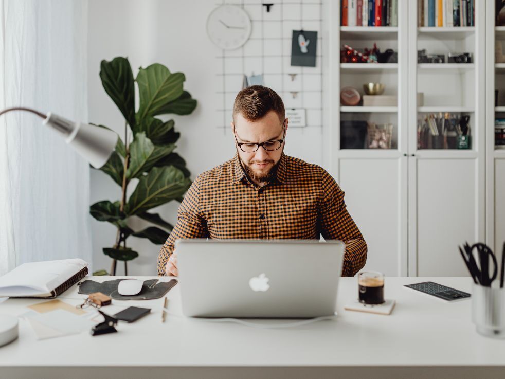 A man is sitting at a desk using a laptop computer.