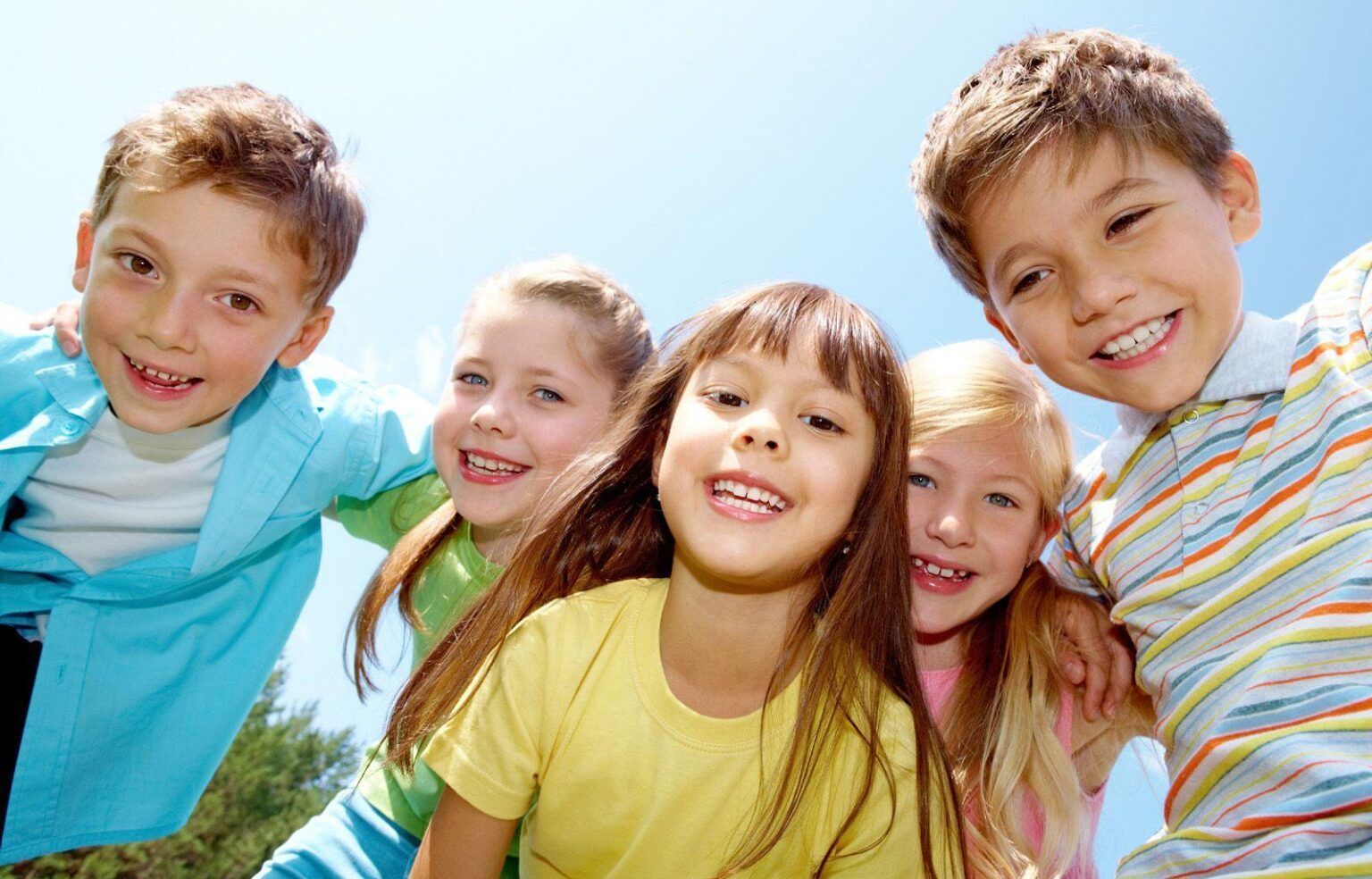 A group of children are posing for a picture together and smiling.