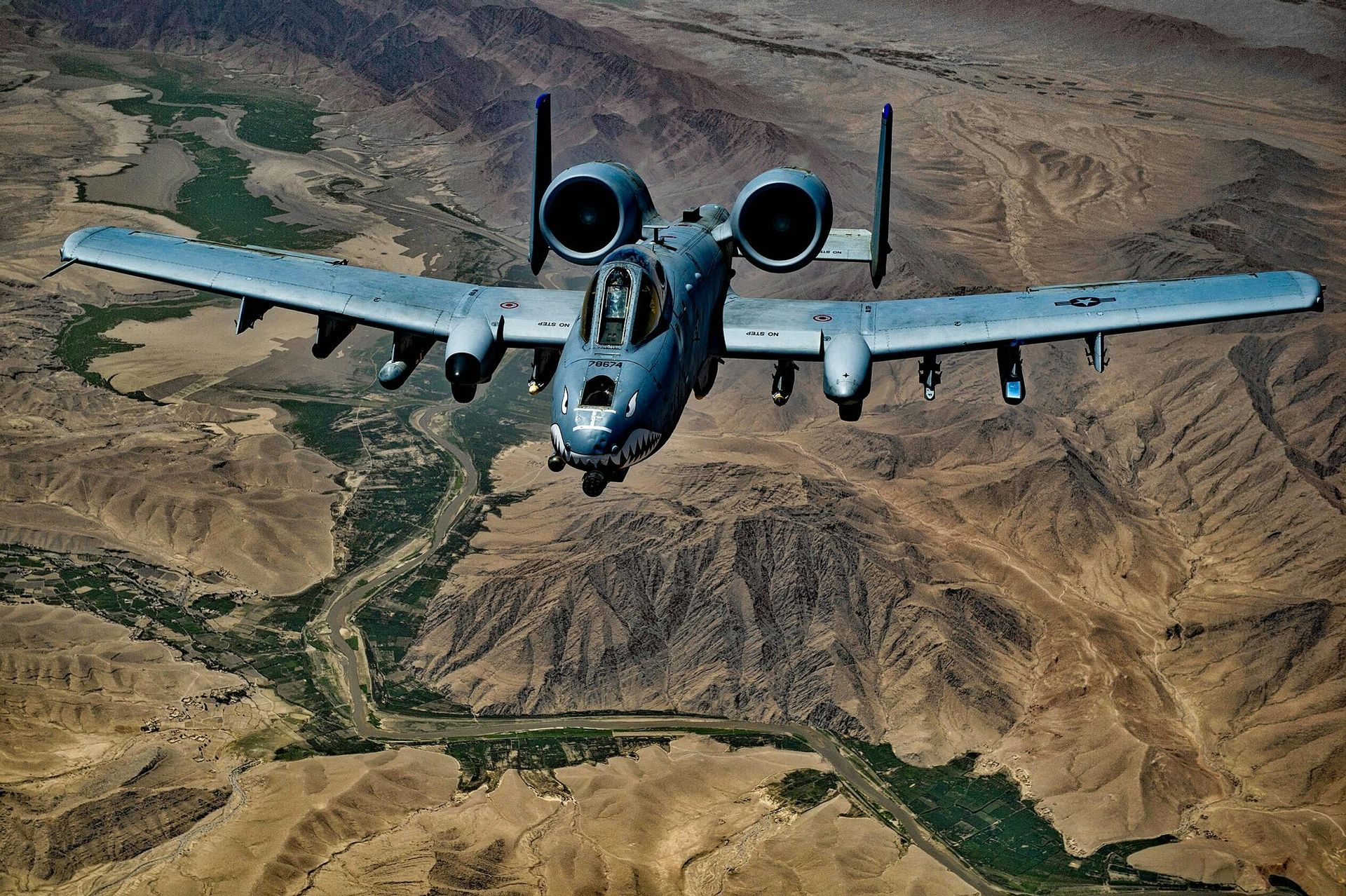 A-10 Thunderbolt II aircraft flies over a desert landscape.
