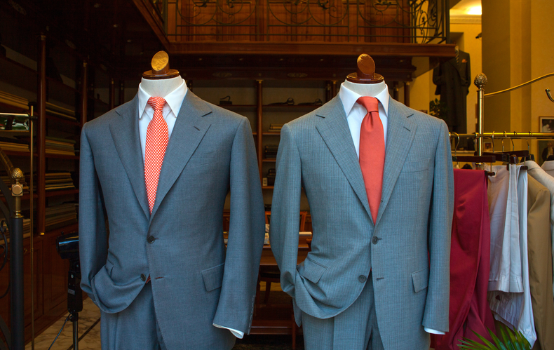 Two mannequins wearing suits and ties in a store