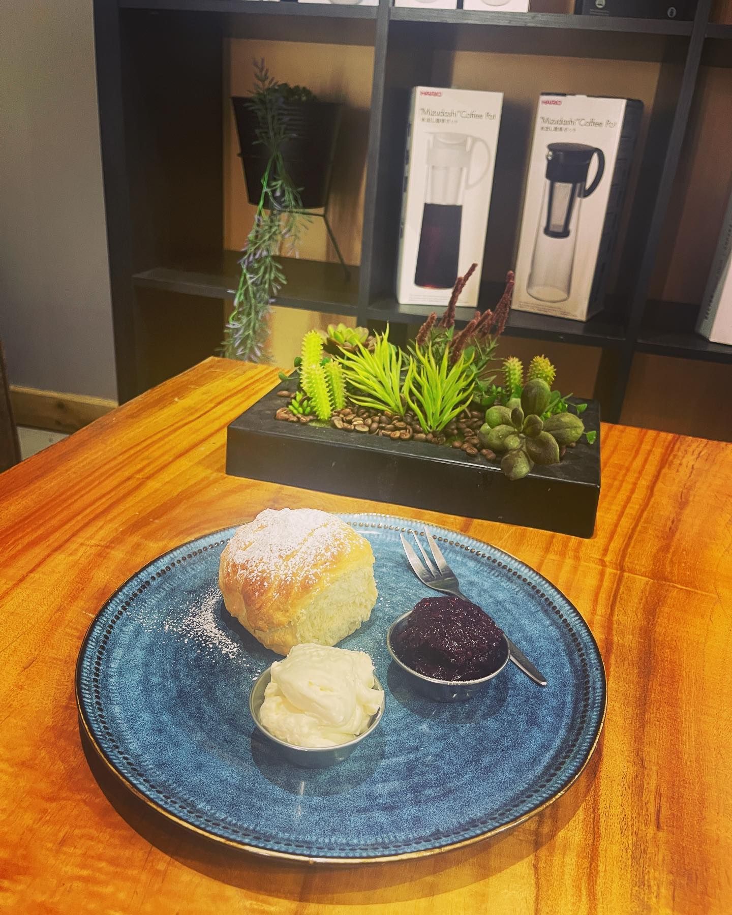 A blue plate topped with a piece of cake , ice cream and jam on a wooden table.