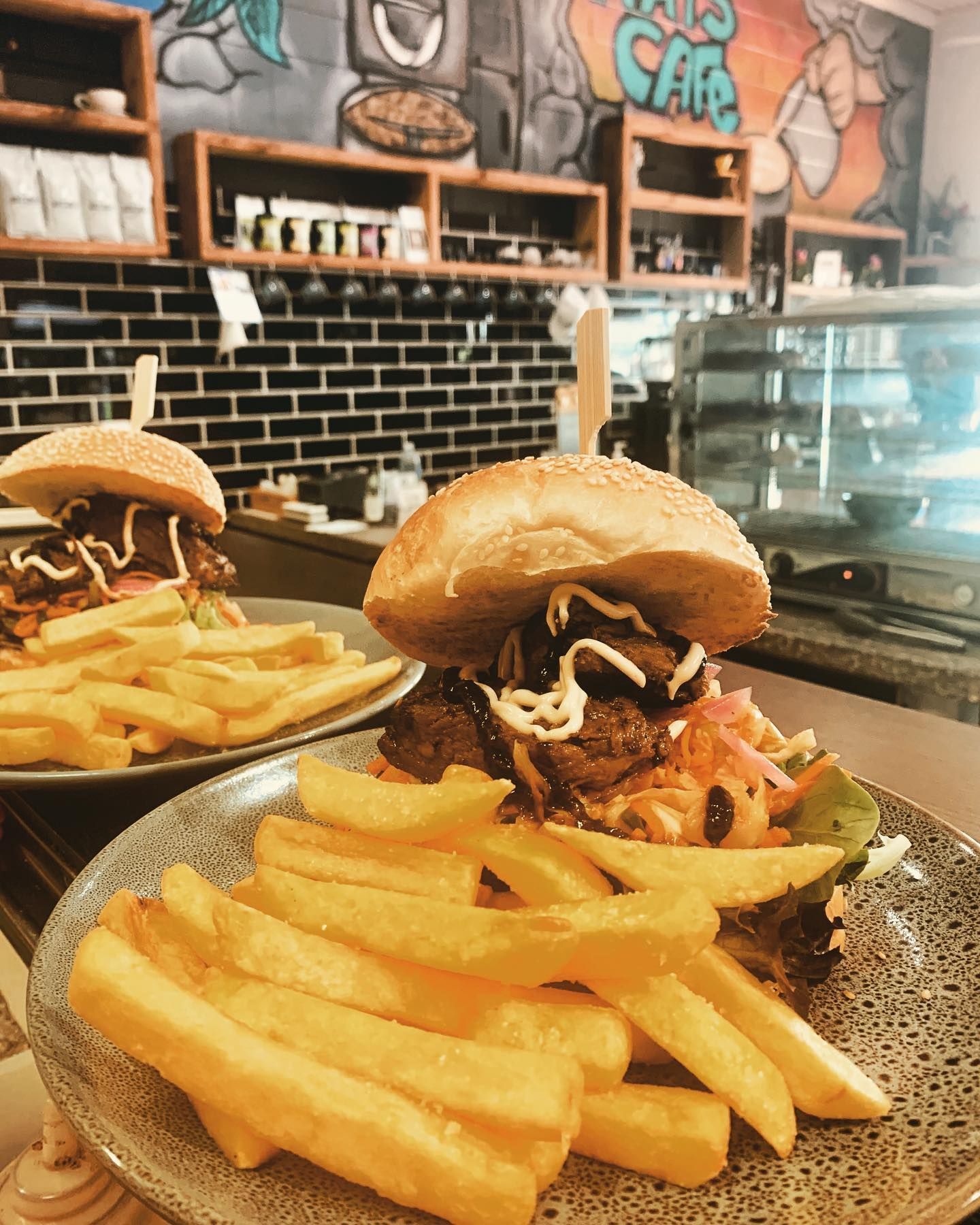 A hamburger and french fries on a plate in a restaurant.