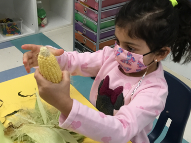 Kid Holding a Corn — Parsippany, NJ — Carousel Of Learning, Early Learning Center & Child Care