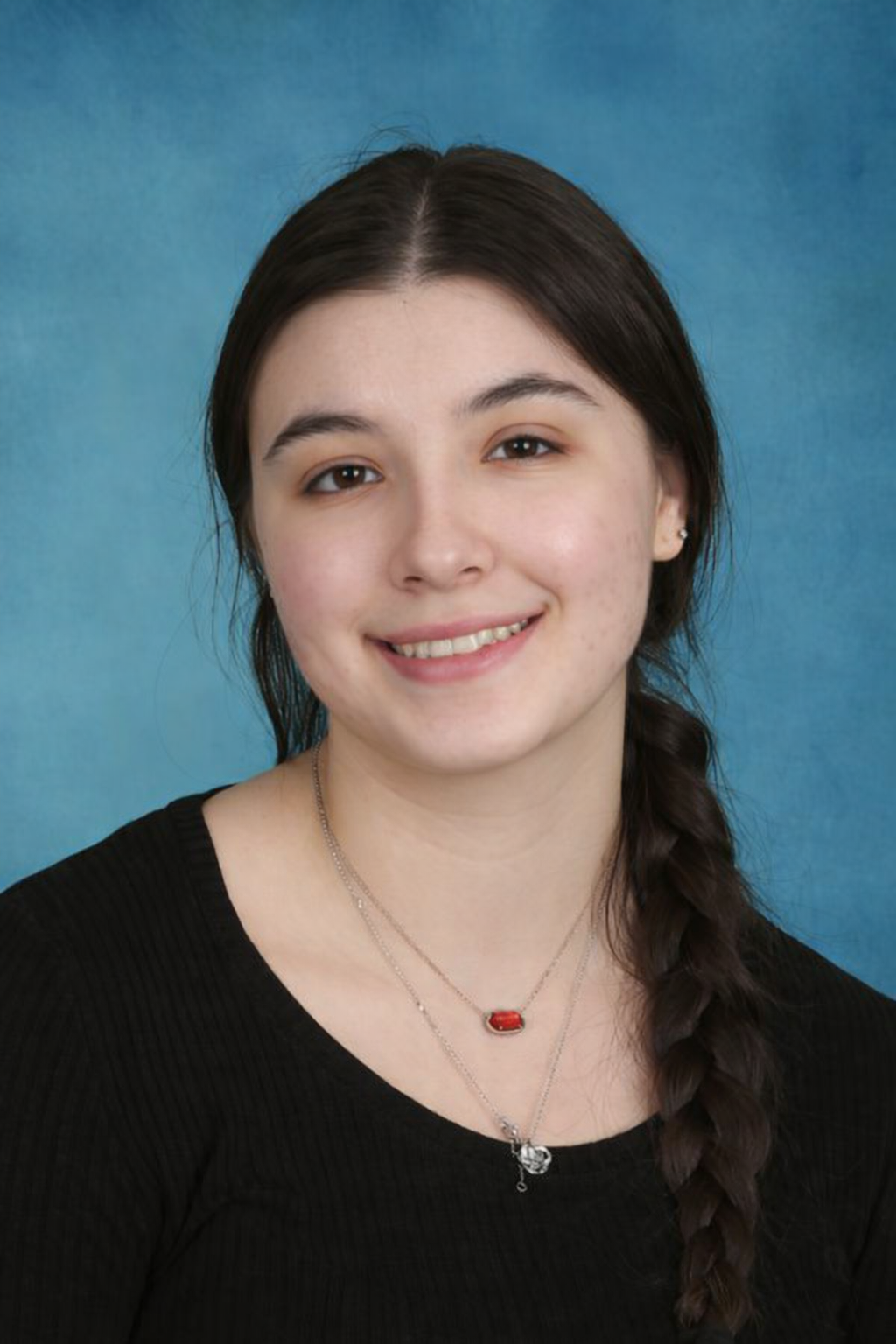 Woman with dark hair smiles, against a blue background.