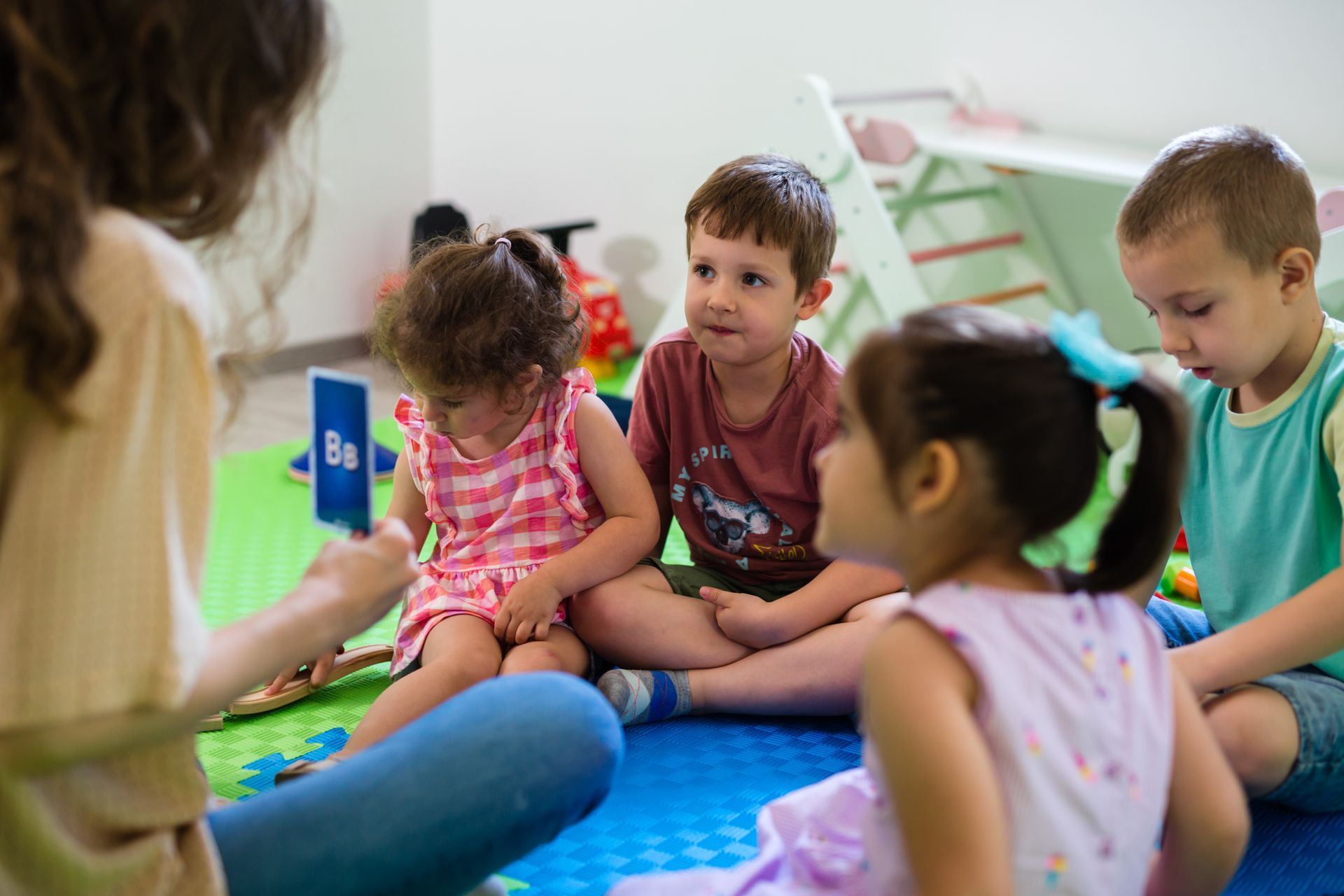The daycare group engaged in playful alphabet learning with caring teacher guidance.