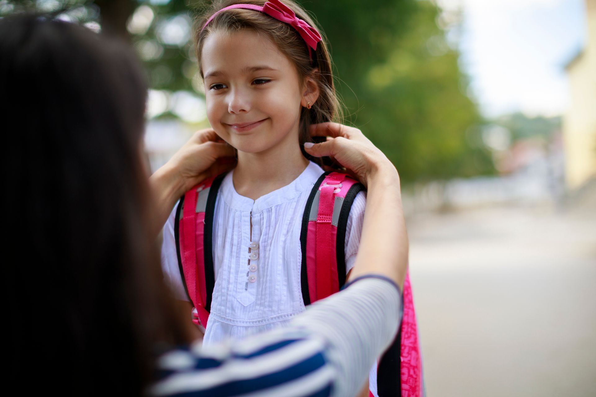 Close-up view of a mother taking her daughter to school.