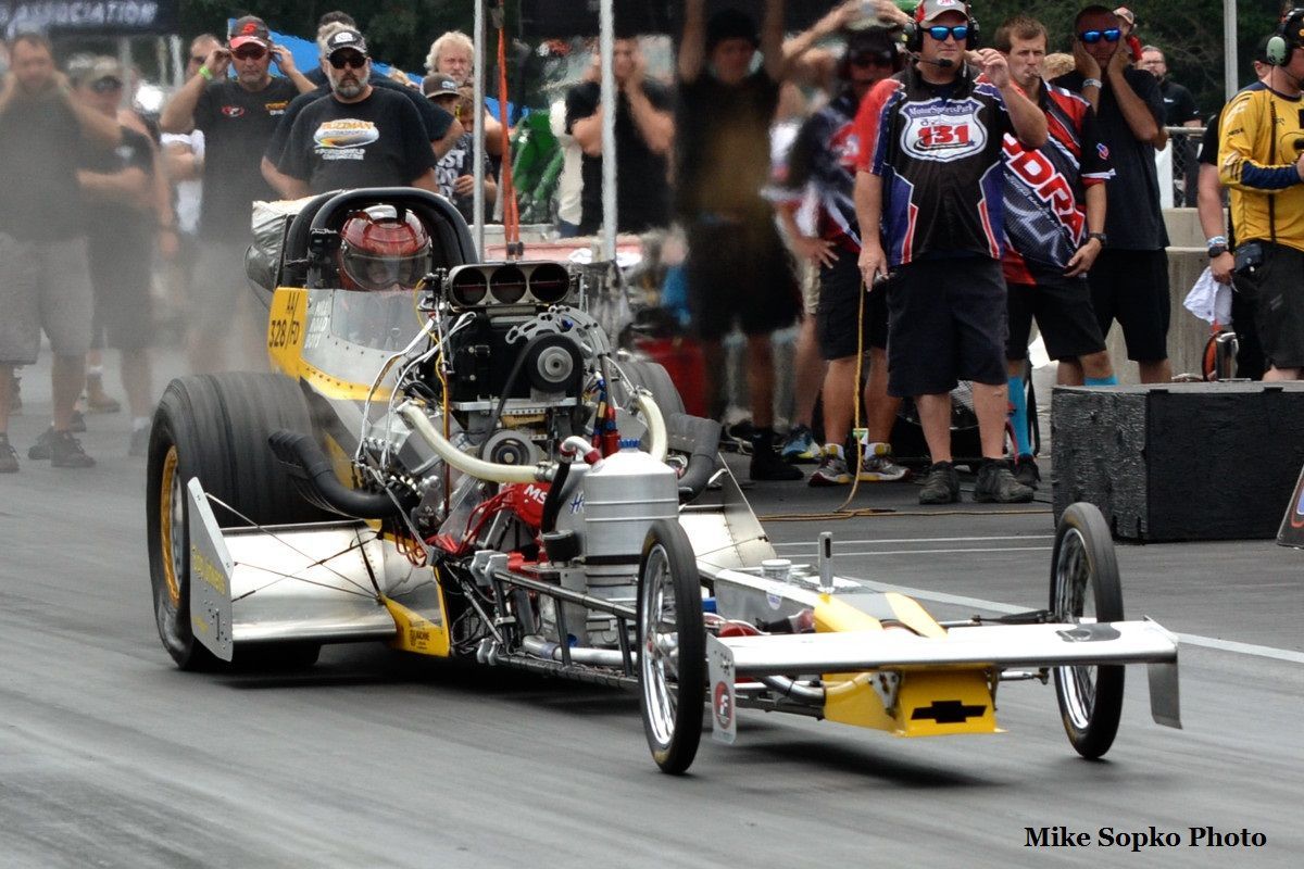 A race car is driving down a track with people watching.