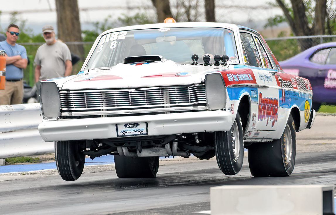 A white and blue car is driving down a race track.