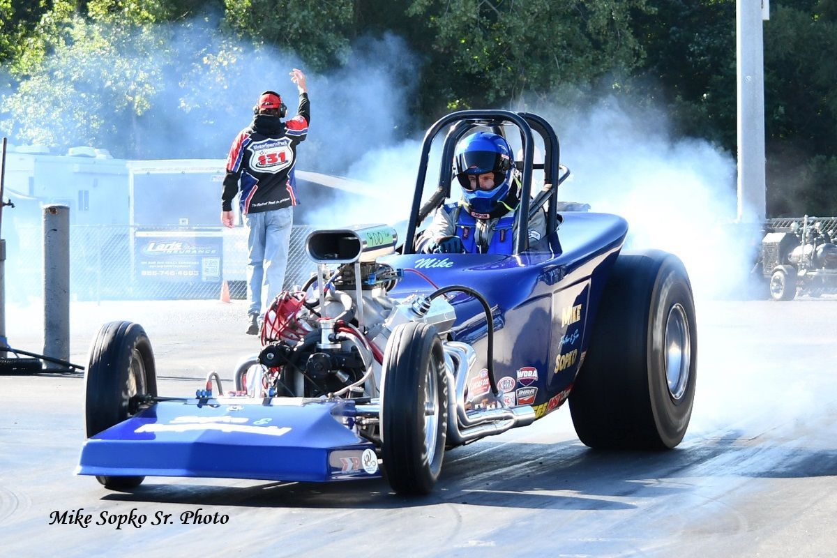 A blue race car is driving down a track with smoke coming out of the tires.