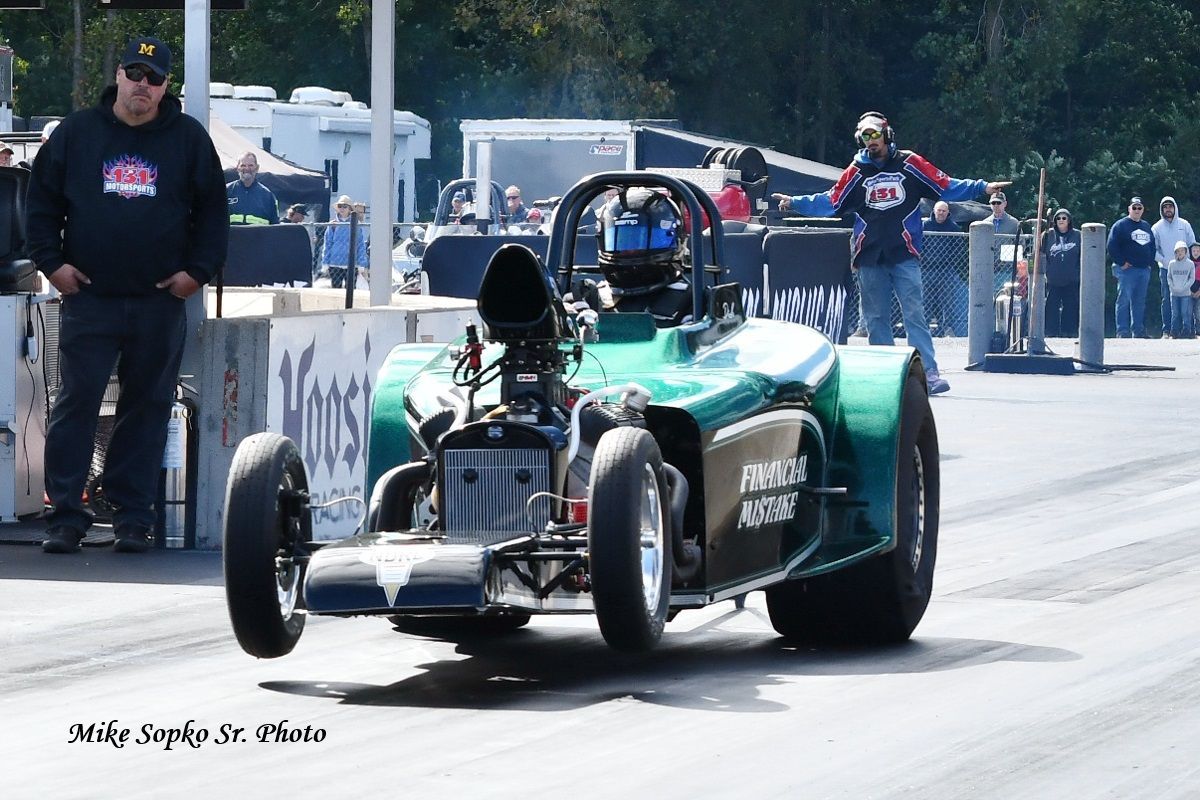 A man stands next to a green race car that says ' rh ' on the side