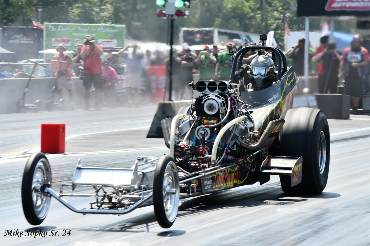 A dragster is driving down a race track.