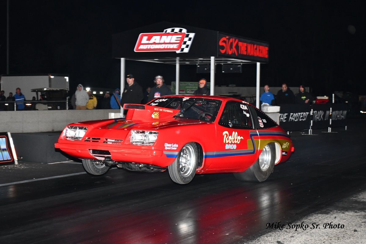 A red race car is parked in front of a lane sign