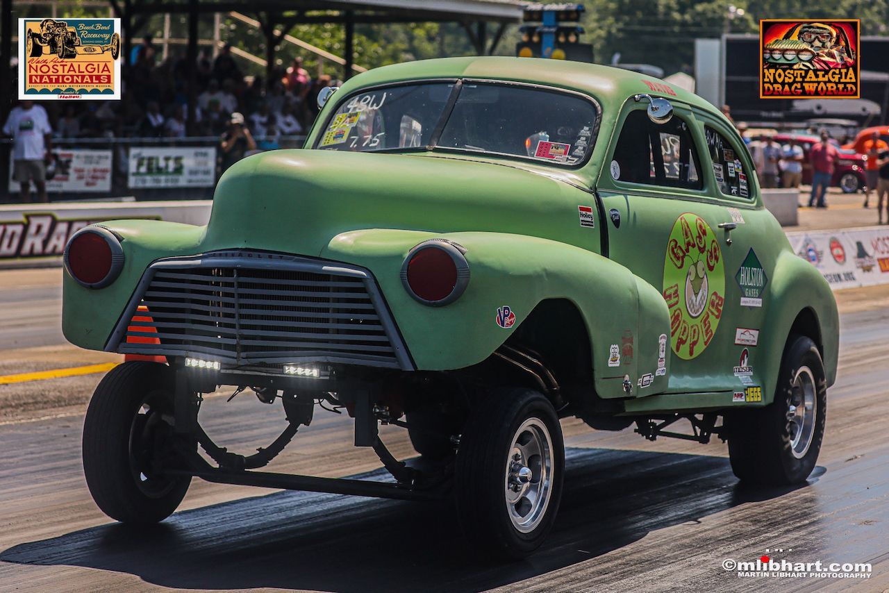 A green car is driving down a race track.