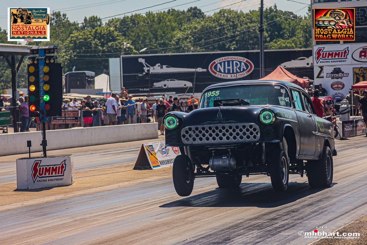 A black car is driving down a race track.