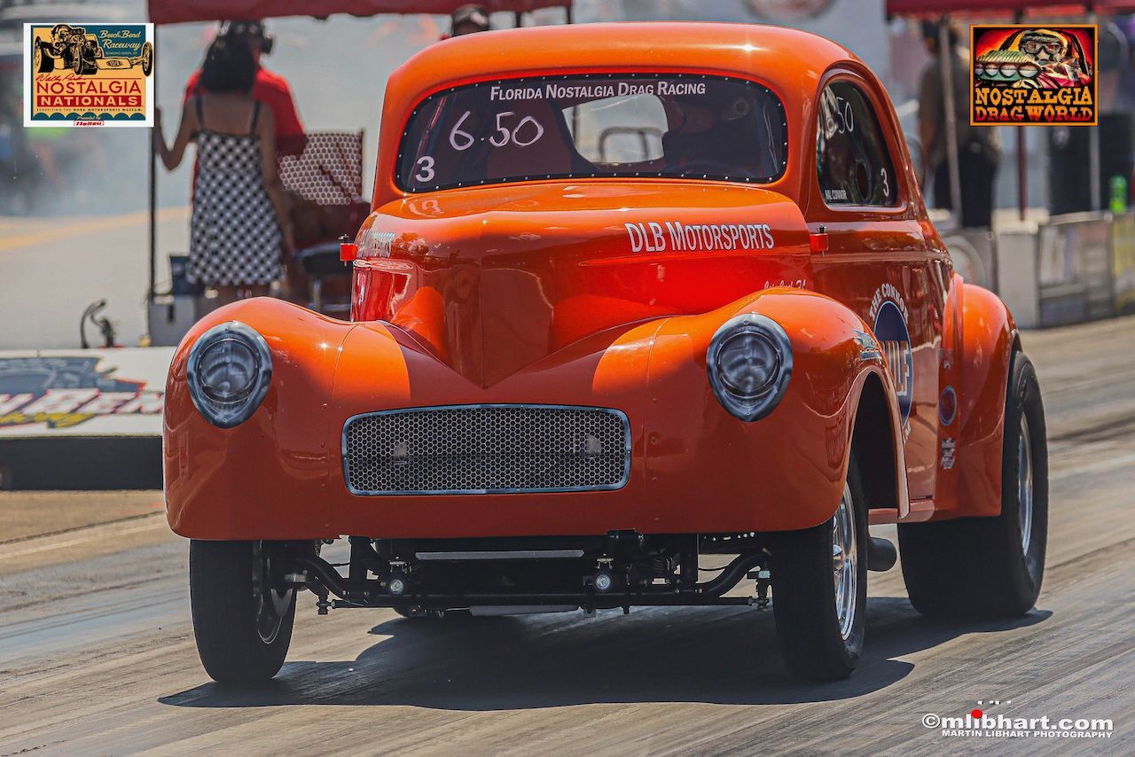 An orange car is driving down a race track.