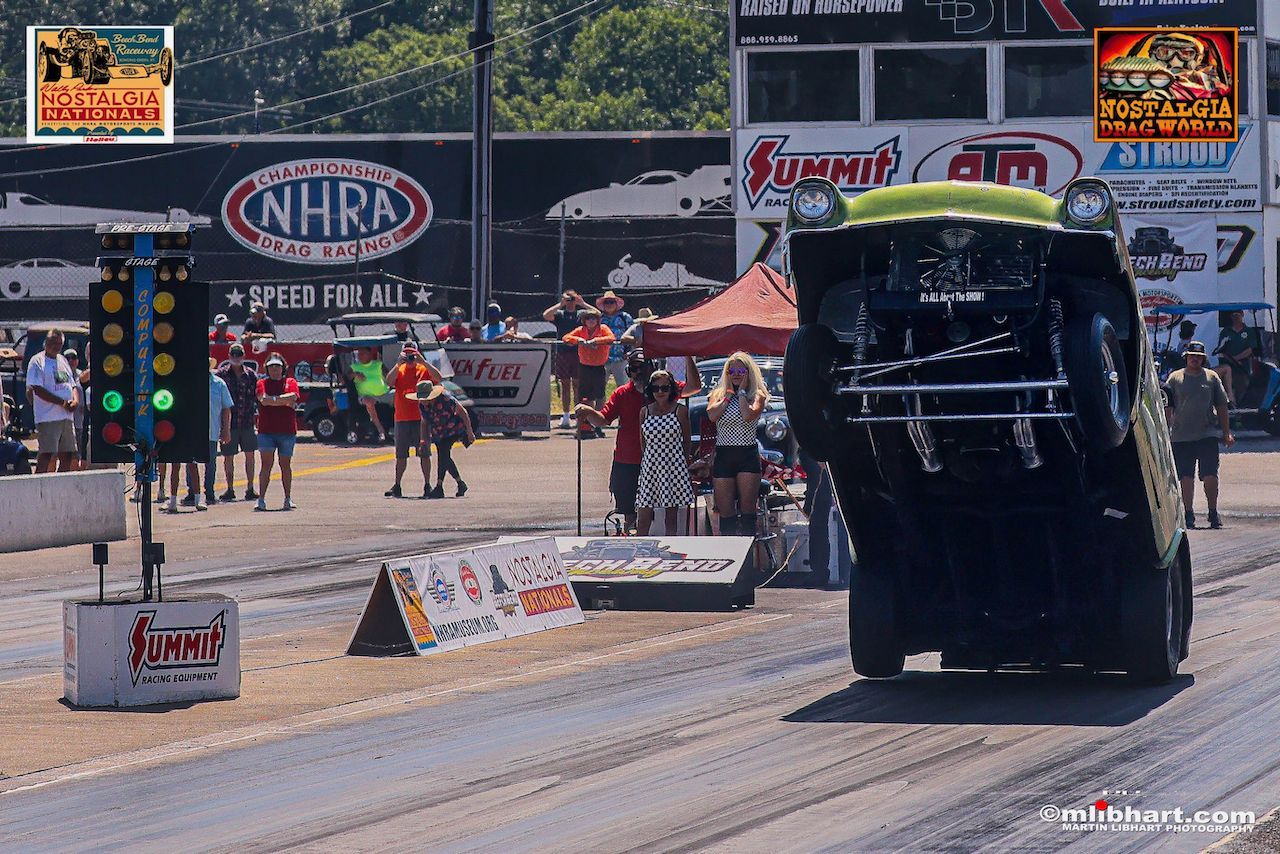 A car is driving down a race track with a nhra sign in the background