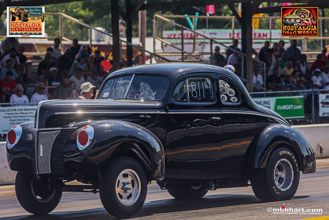 A black car is driving down a race track.