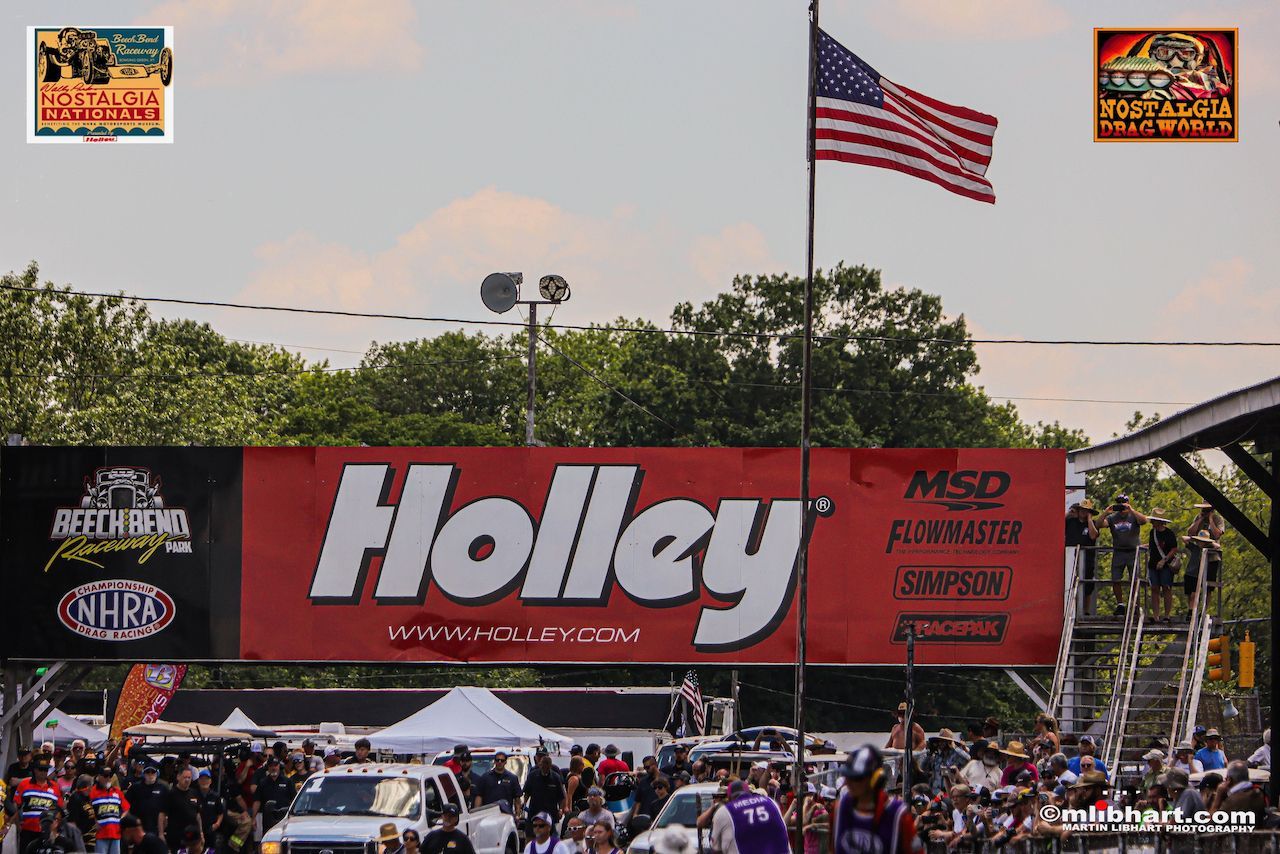 A crowd of people are gathered in front of a holly sign