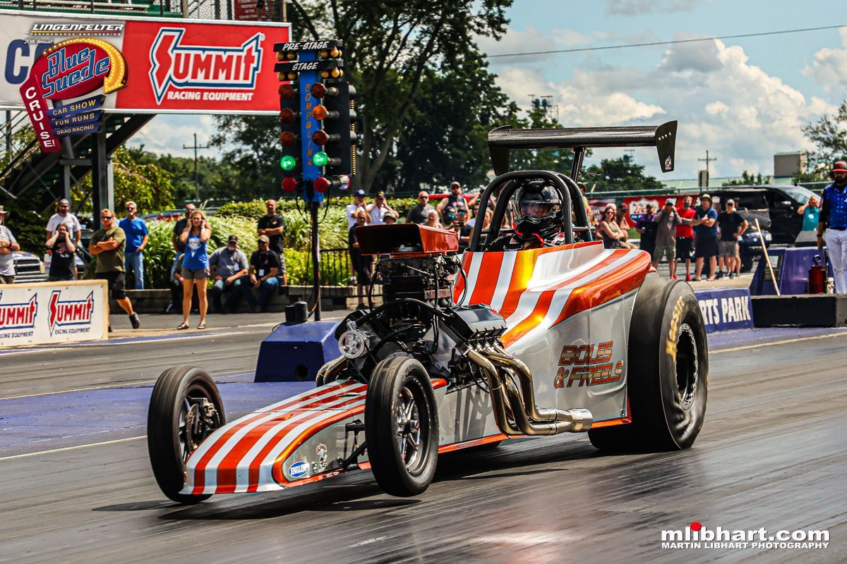 A race car is driving down a race track with a summit sign in the background.